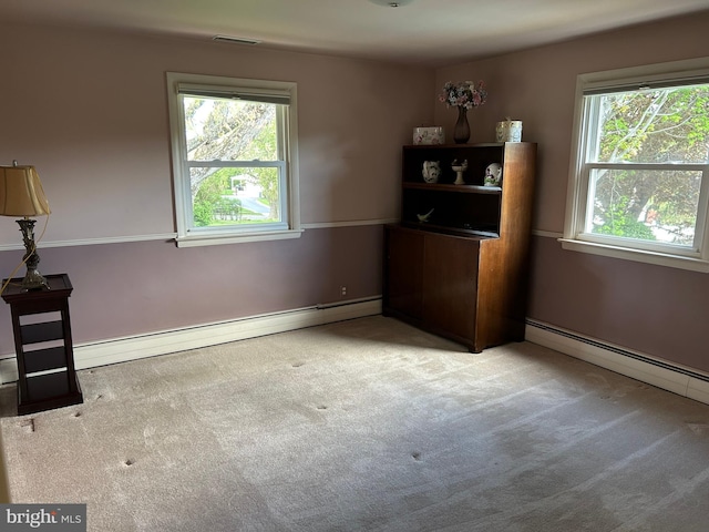 empty room featuring a wealth of natural light, a baseboard heating unit, and carpet