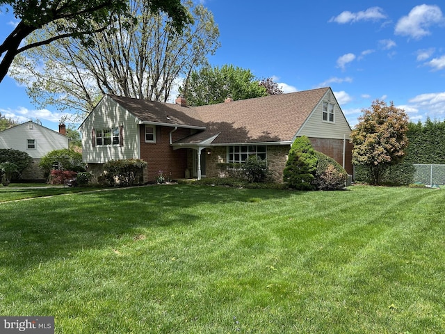 view of front facade with a front lawn, fence, a chimney, and brick siding