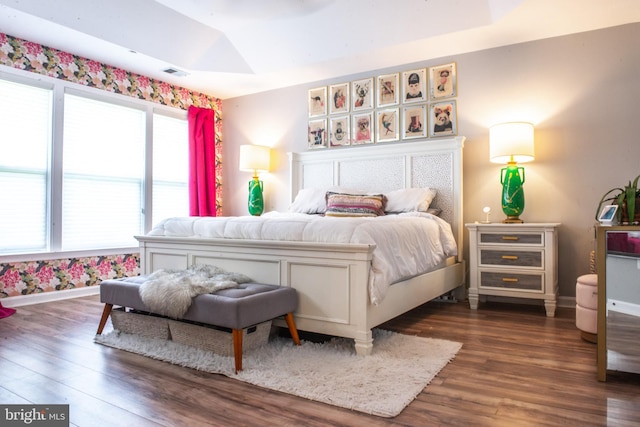 bedroom with visible vents, dark wood-style flooring, lofted ceiling, and baseboards
