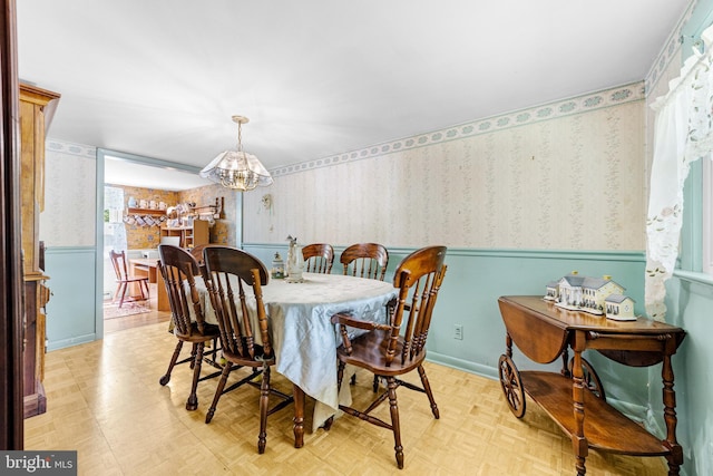 dining space featuring a wainscoted wall, wallpapered walls, and a notable chandelier