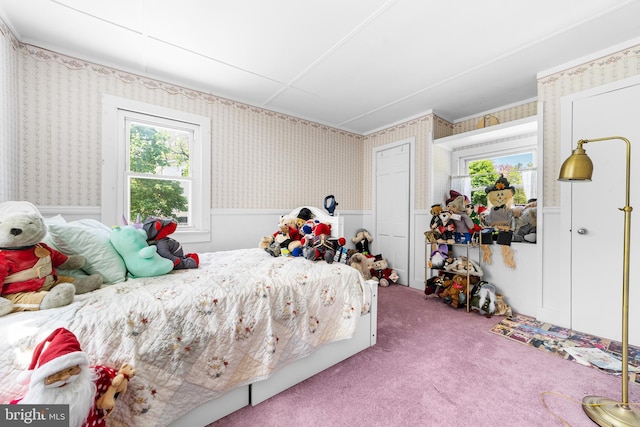 bedroom featuring wallpapered walls, wainscoting, and carpet