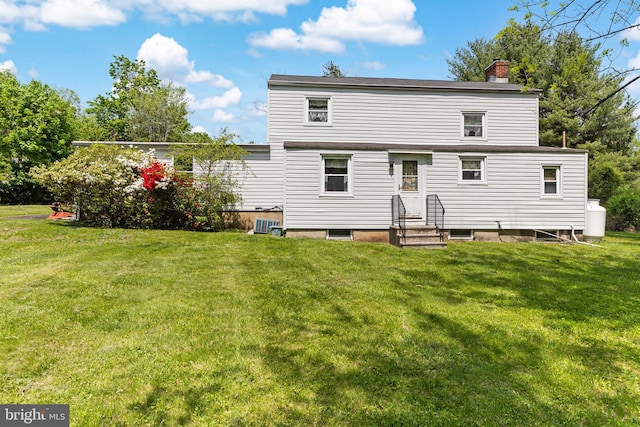 back of house with a lawn, a chimney, and entry steps