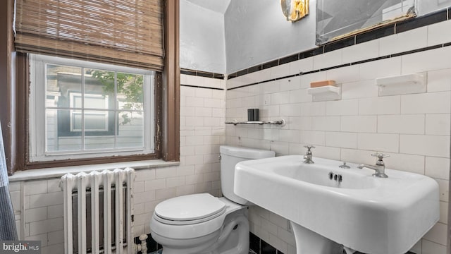 bathroom featuring toilet, tile walls, a sink, and radiator