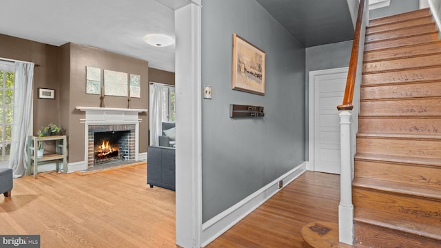 stairway featuring baseboards, wood finished floors, and a fireplace