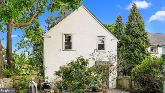 view of side of home featuring fence and stucco siding
