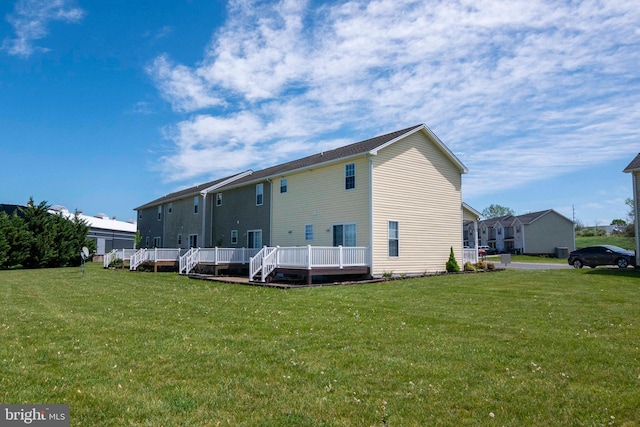 back of house with a wooden deck and a lawn