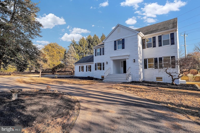 view of front of home with brick siding, driveway, and roof with shingles