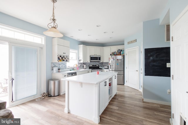 kitchen with decorative backsplash, stainless steel appliances, light wood-style floors, light countertops, and a sink