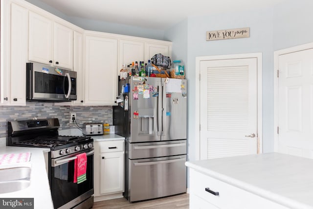 kitchen with stainless steel appliances, light countertops, and white cabinets