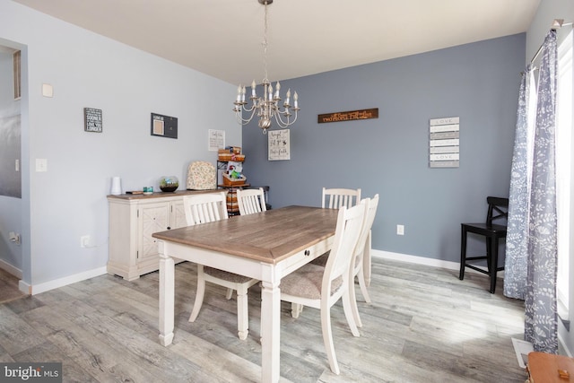dining space featuring a chandelier, baseboards, and light wood-style floors
