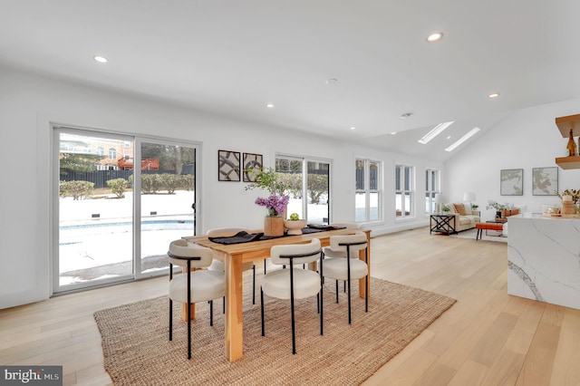 dining room with light wood-style floors, vaulted ceiling with skylight, and recessed lighting