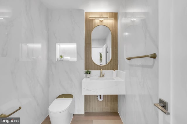 bathroom featuring a sink, toilet, and tile walls