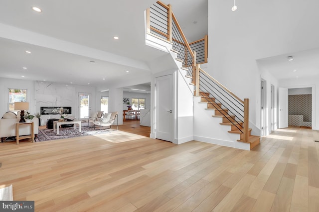 entrance foyer featuring recessed lighting, light wood-type flooring, stairs, and a premium fireplace