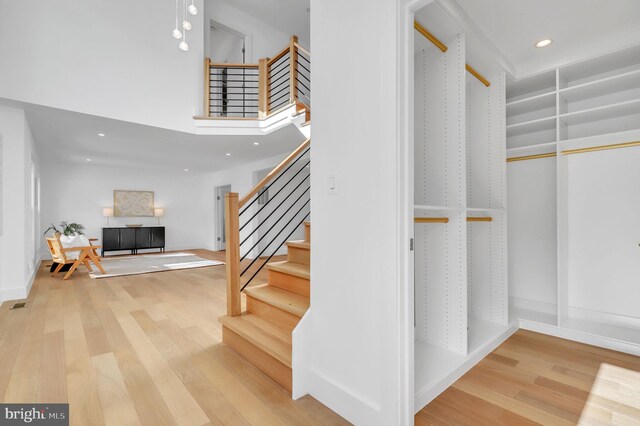 stairway with a high ceiling, recessed lighting, and wood finished floors