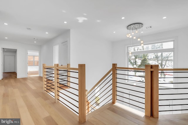 hall featuring visible vents, baseboards, recessed lighting, light wood-style flooring, and an upstairs landing