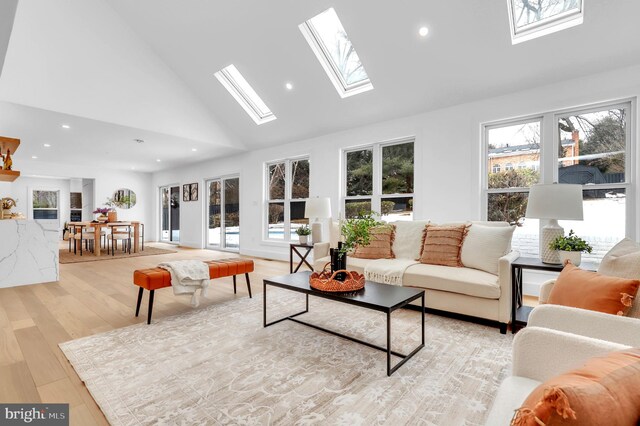 living room featuring recessed lighting, a skylight, high vaulted ceiling, and light wood-type flooring