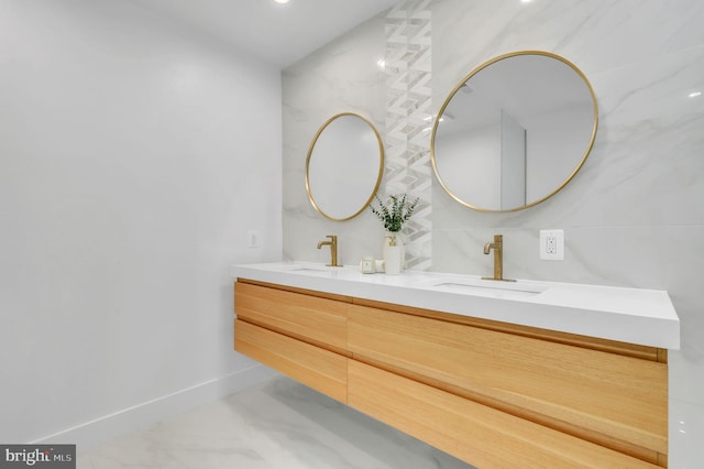 bathroom with a sink, baseboards, double vanity, and marble finish floor