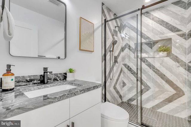 bathroom featuring toilet, visible vents, a shower stall, and vanity