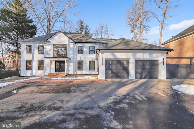 view of front facade with stucco siding, an attached garage, fence, and aphalt driveway