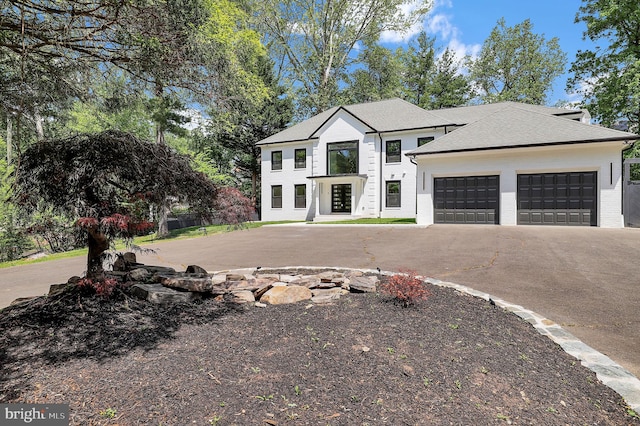 view of front facade with a garage, a shingled roof, and driveway