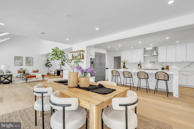 dining room featuring recessed lighting, light wood-style flooring, and vaulted ceiling