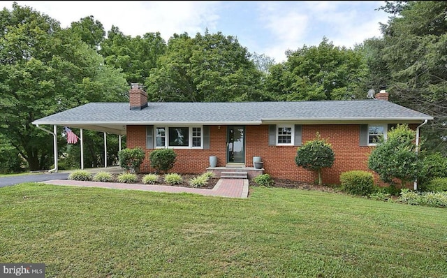 ranch-style house featuring a chimney, a front yard, brick siding, and a carport
