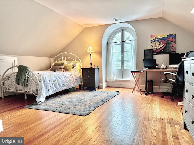 bedroom with vaulted ceiling, wood-type flooring, and a desk
