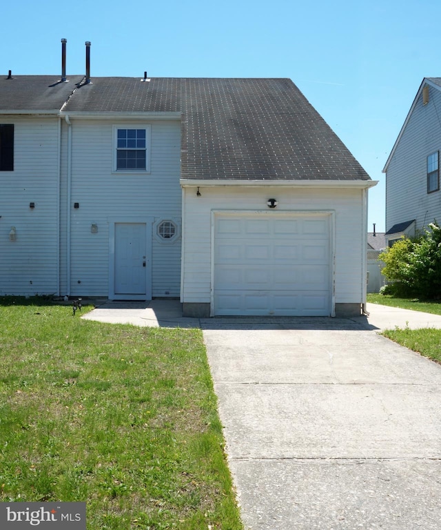 multi unit property with an attached garage, concrete driveway, and a front lawn