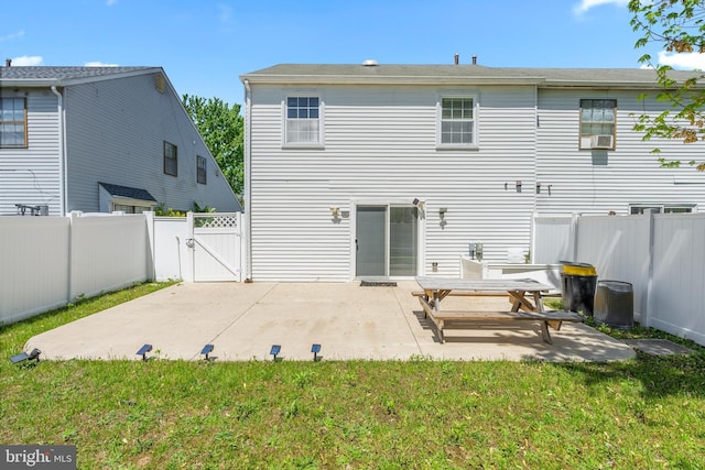 rear view of house featuring a fenced backyard, a gate, a yard, and a patio area