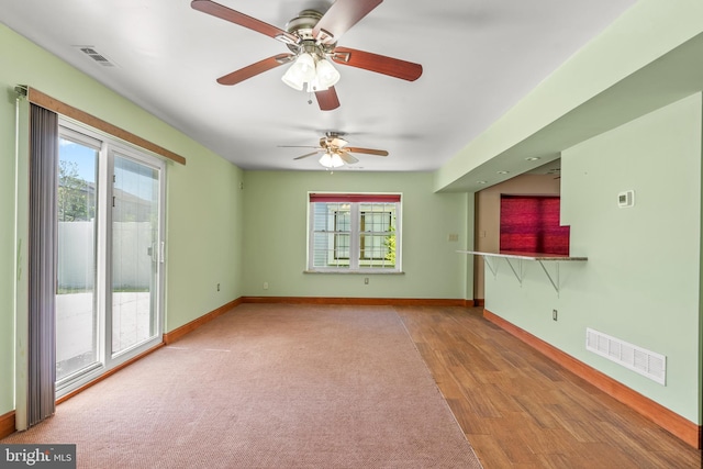 unfurnished living room with baseboards, a ceiling fan, wood finished floors, and visible vents