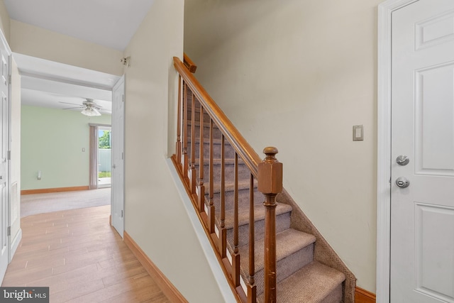 stairway featuring a ceiling fan, baseboards, and wood finished floors
