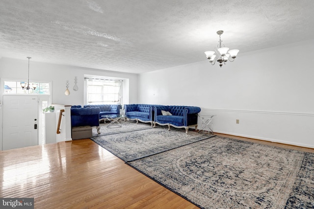living room with a chandelier, a textured ceiling, and wood finished floors