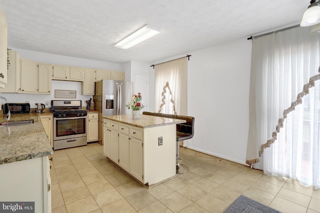 kitchen with a sink, a textured ceiling, a kitchen bar, a kitchen island, and appliances with stainless steel finishes