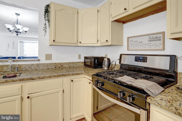 kitchen with a sink, stainless steel gas range oven, pendant lighting, light stone countertops, and a notable chandelier