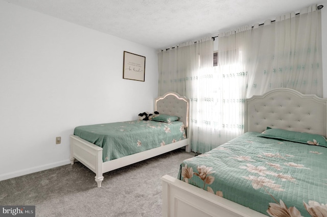 carpeted bedroom featuring a textured ceiling and baseboards