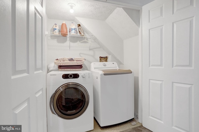 washroom featuring laundry area, washer and clothes dryer, and a textured ceiling