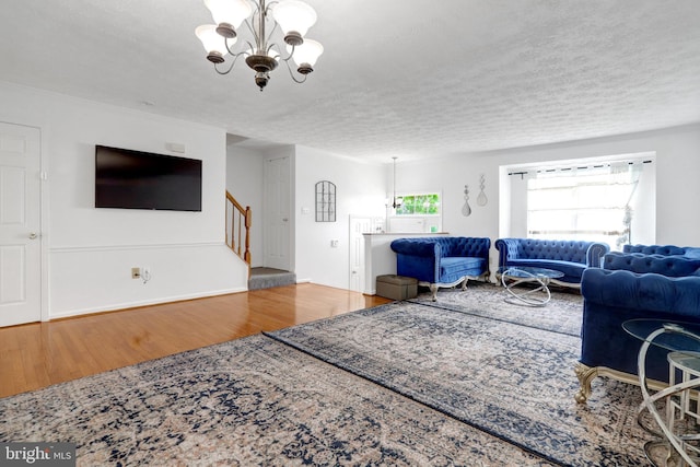living area featuring stairway, an inviting chandelier, a textured ceiling, and wood finished floors