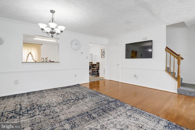 living room with a chandelier, stairs, ornamental molding, and wood finished floors