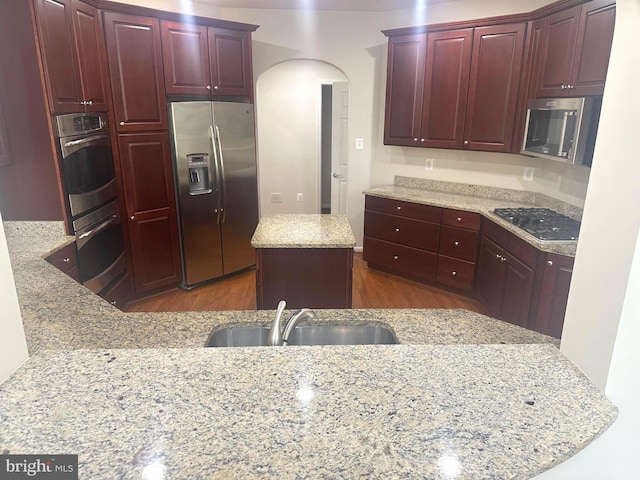 2435 Mill Race Rd, Frederick, MD 21701 - kitchen featuring arched walkways, reddish brown cabinets, stainless steel appliances, and a sink