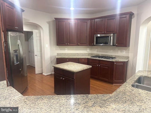 2435 Mill Race Rd, Frederick, MD 21701 - kitchen with wood finished floors, arched walkways, light stone countertops, reddish brown cabinets, and appliances with stainless steel finishes