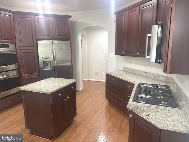 2435 Mill Race Rd, Frederick, MD 21701 - kitchen featuring stainless steel appliances, light wood-style flooring, arched walkways, light stone countertops, and a kitchen island
