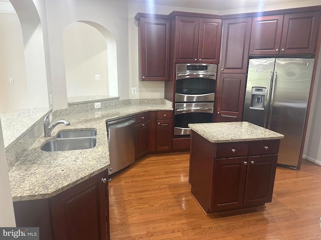 2435 Mill Race Rd, Frederick, MD 21701 - kitchen featuring a sink, stainless steel appliances, wood finished floors, arched walkways, and light stone countertops