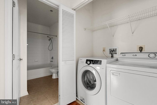 clothes washing area featuring light tile patterned flooring and washing machine and clothes dryer
