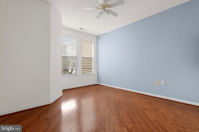 unfurnished room featuring wood finished floors, visible vents, a ceiling fan, and baseboards