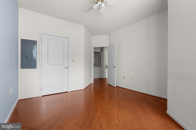 unfurnished bedroom with a ceiling fan, electric panel, wood finished floors, and baseboards