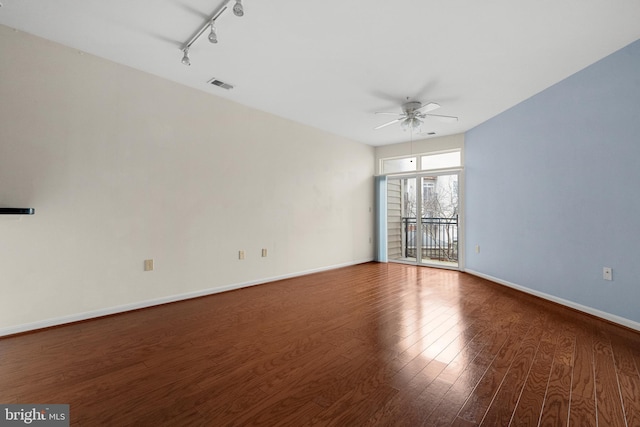 spare room featuring visible vents, baseboards, track lighting, wood finished floors, and a ceiling fan