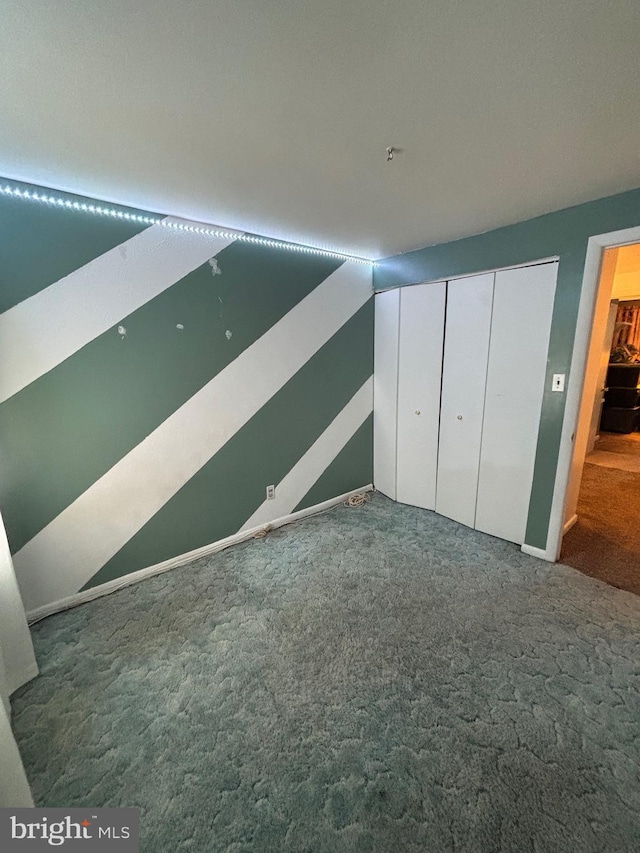 unfurnished bedroom with dark carpet and a closet