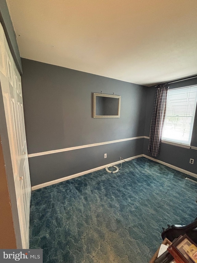 spare room featuring carpet floors and baseboards