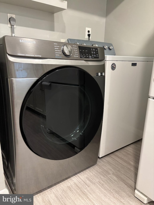 clothes washing area featuring washing machine and dryer and light wood-style floors