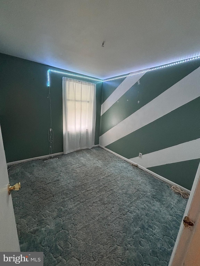 unfurnished room with carpet flooring and baseboards